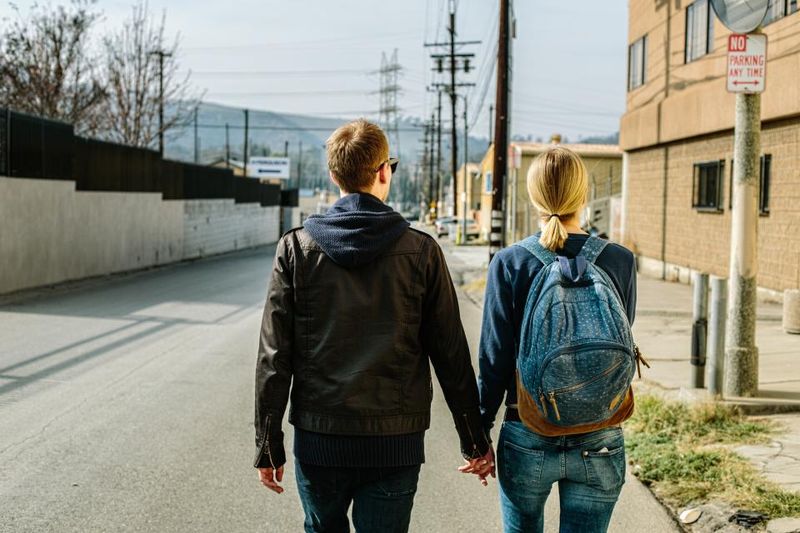 Two travelers from behind with their bags